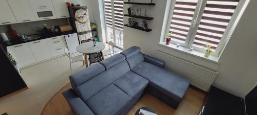 a living room with a blue couch and a kitchen at Apartament Turysty Zamczysko in Zamość