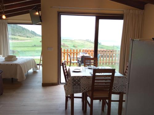 ein Esszimmer mit Tisch und Stühlen und einem großen Fenster in der Unterkunft Camping Playa de Nemiña in Nemiña