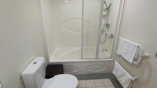 a white bathroom with a shower and a toilet at Big Save at St Lukes Quiet House in Auckland