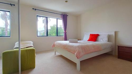 a bedroom with a bed with a red pillow and a window at Big Save at St Lukes Quiet House in Auckland