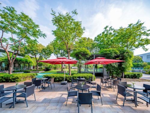 a patio with tables and chairs and red umbrellas at Holiday Inn Shanghai Pudong Kangqiao by IHG - Free shuttle bus to Disney land, Ins Swimming Pool in Shanghai