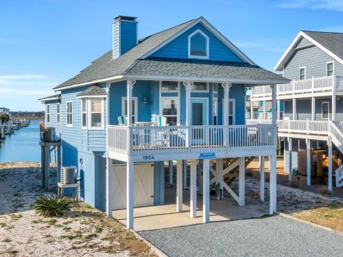 a blue house with a balcony on the beach at The Last Dollar Cottage in Topsail Beach