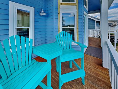 two chairs and a table on the porch of a blue house at The Last Dollar Cottage in Topsail Beach
