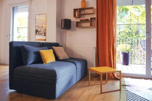 - un canapé bleu dans le salon doté d'une fenêtre dans l'établissement SweetHomeVersailles 10mn walk from Palace, à Versailles