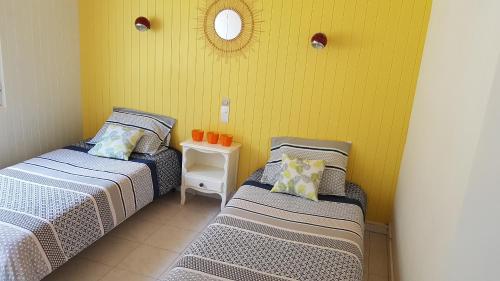- 2 lits dans une chambre dotée d'un mur jaune dans l'établissement Appartement de 85 m2 au cœur de Carnac plage, à Carnac