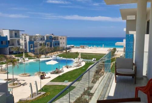 a balcony with a view of a pool and the ocean at luxurious chalet in Fouka Bay North Coast in Zāwiyat al ‘Awwāmah