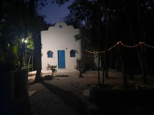 un petit bâtiment blanc avec une porte bleue la nuit dans l'établissement If you enjoy nature, La Antigua is the place, à Leona Vicario