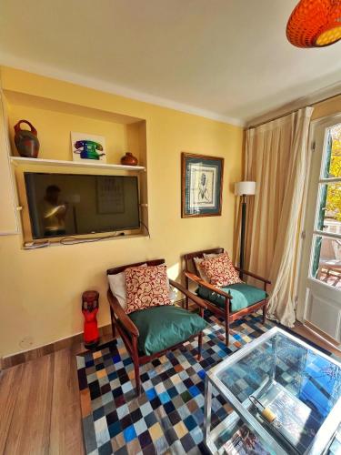 a living room with two chairs and a flat screen tv at Pato’s Guest House in Mendoza