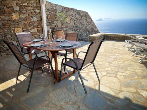 a wooden table and chairs on a patio with the ocean at Cosy villa with infinity pool and amazing view in Kithnos