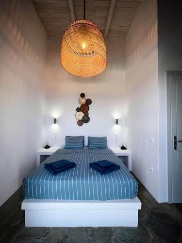 a bedroom with a bed with blue pillows and a chandelier at Cosy villa with infinity pool and amazing view in Kithnos