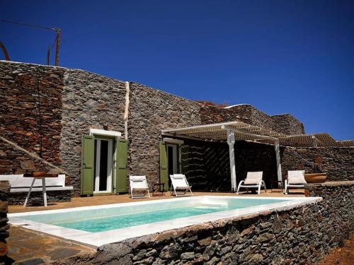 a swimming pool with chairs and a stone house at Cosy villa with infinity pool and amazing view in Kithnos