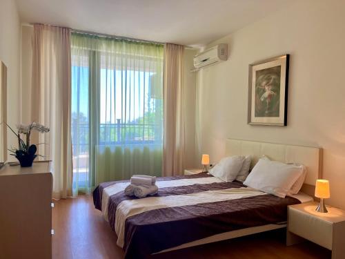 een slaapkamer met een groot bed en een groot raam bij Бяла Виста Бийч Апартментс B - Byala Vista Beach Apartments B in Byala