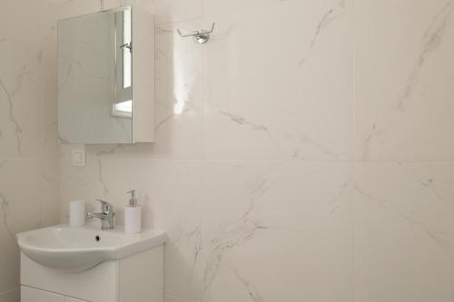 a white bathroom with a sink and a mirror at Agatha's central bright modern luxury apartment-2 in Perítheia