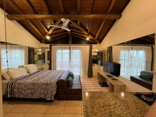 una camera da letto con un letto, un divano e una televisione di Lofts Asa Delta apartamento com cozinha a Ilhabela