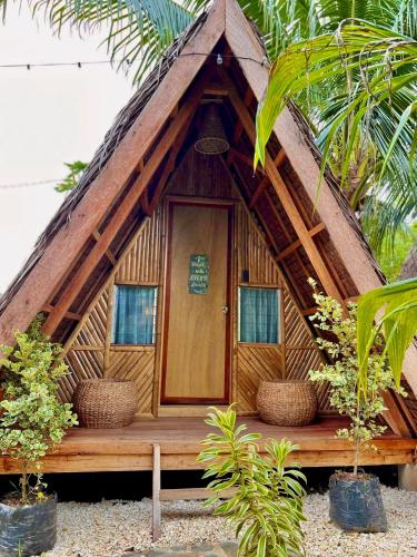 a thatch roofed hut with a wooden door at Bohol Island Homestay in Dauis