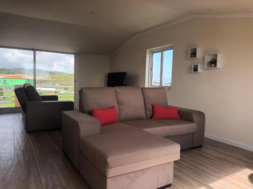 a living room with a brown couch and red pillows at Casa do Capitão-Mor in São Mateus