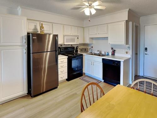 a kitchen with white cabinets and a stainless steel refrigerator at A Place At The Beach #1D in Carolina Beach