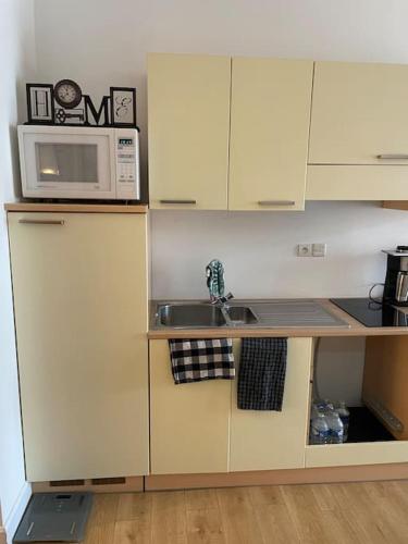 une petite cuisine avec un évier et un micro-ondes dans l'établissement Studio proche du Luxembourg, à Aumetz