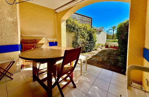 une table et des chaises en bois sur un porche avec un patio dans l'établissement Résidence les parcs de Grimaud du golf de Saint Tropez, à Grimaud
