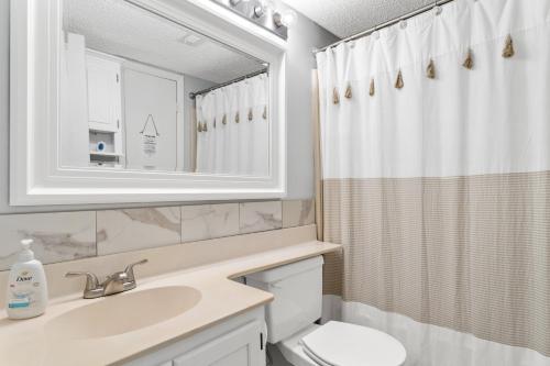 a bathroom with a sink and a toilet and a mirror at A Wave From It All in North Topsail Beach