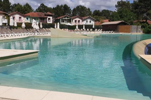 - une piscine d'eau bleue en face des maisons dans l'établissement Bienvenue à l'Appart' !, à Lacanau