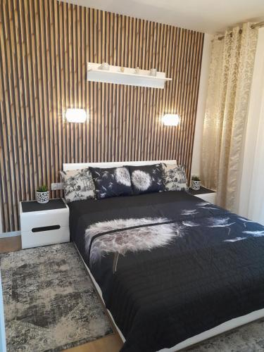 a bedroom with a black bed and a striped wall at Nadmorskie Apartamenty w Gąskach in Gąski
