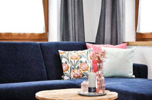 a blue couch with pillows and a table with a candle at Hüs Uis in Sonthofen