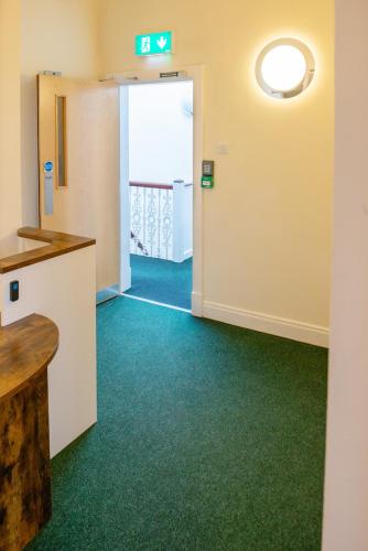 a corridor of a hospital room with green carpet at Botanic Avenue Hostel less than a mile from the City Centre in Belfast