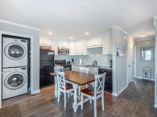 a kitchen with a table and chairs and a washer and dryer at Coral Surf #A1 - Beachy Keen in Carolina Beach