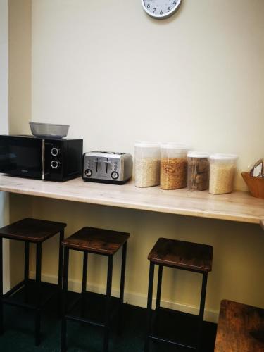 a counter with two stools and a counter top with a microwave at Botanic Avenue Hostel less than a mile from the City Centre in Belfast