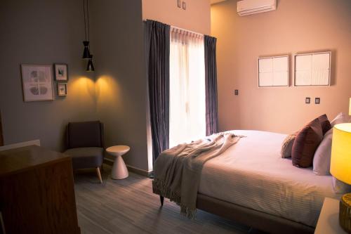 a bedroom with a bed and a window and a chair at Hotel Boutique Corazón Mexicano in Guanajuato