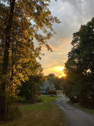 a house on a street with the sunset in the background at Experience the Charm of a Cozy Hudson Valley Vacation Retreat in Gardiner