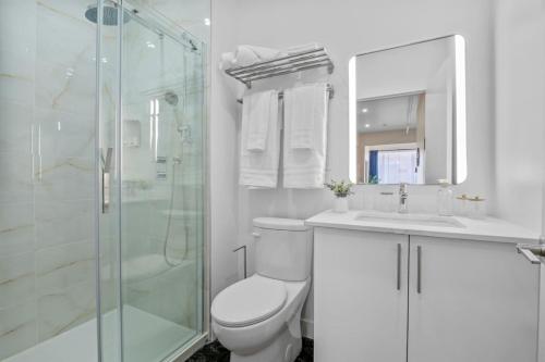 a white bathroom with a toilet and a shower at Central King Studio in Montreal