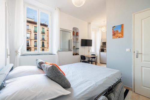 une chambre blanche avec un lit et une fenêtre dans l'établissement FELIX FAURE - Charmant studio lumineux en centre-ville, à Menton