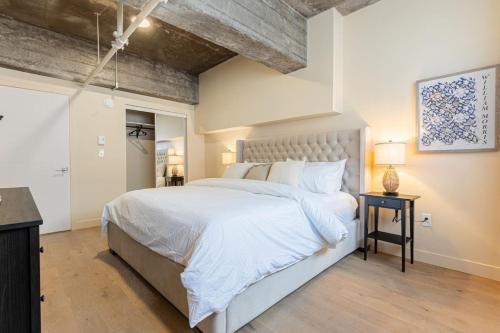 a bedroom with a large white bed and a wooden floor at Double King Luxury 2BR Condo in Montréal