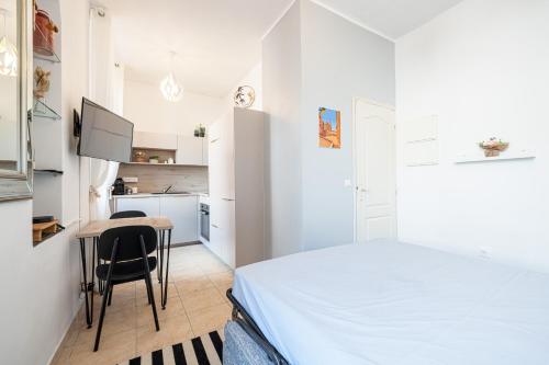 une petite chambre blanche avec une table et un lit dans l'établissement FELIX FAURE - Charmant studio lumineux en centre-ville, à Menton