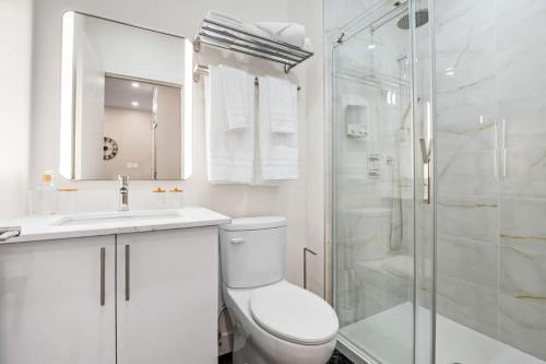a white bathroom with a toilet and a shower at Central Studio in Montréal