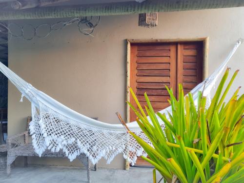 a hammock in front of a house with a door at Chalés Refúgio Fortim in Fortim