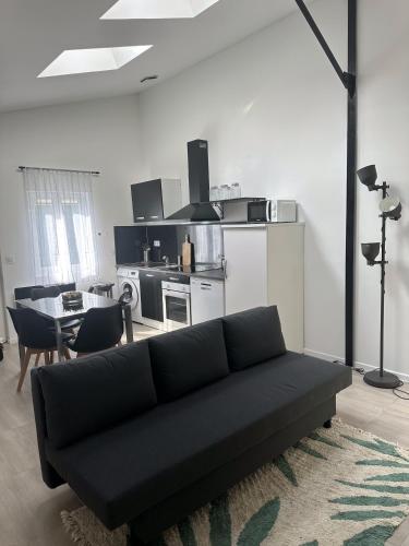 a living room with a black couch and a kitchen at Cosy Home Stade de france in Aubervilliers