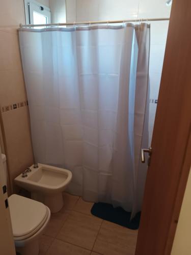 a bathroom with a toilet and a shower curtain at Diez ApartHotel in Puerto Madryn