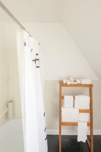 a bathroom with a shower curtain and a shelf with towels at Maison du Havre Petit Duplex in La Malbaie