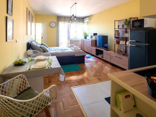 a living room with a kitchen and a room with a refrigerator at Green Apple Apartment in Subotica