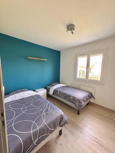 une chambre avec deux lits et un mur bleu dans l'établissement Maison chaleureuse avec piscine, à Izon