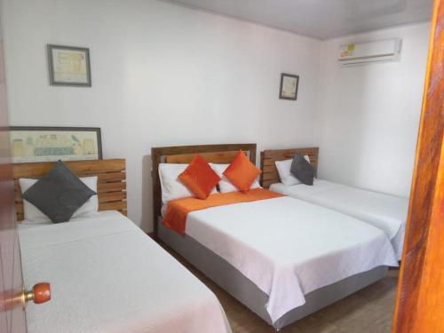 um quarto com 2 camas com almofadas laranja em Hotel Campestre Maguey em Mangue