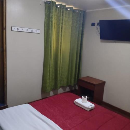 a bedroom with a bed with a red blanket and a window at Hostal Jara in Lima