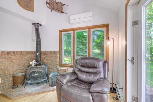 a leather chair in a living room with a fireplace at Alden Home with Fire Pit Steps to Torch Lake! in Alden