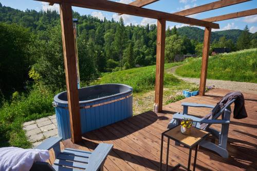 a wooden deck with a hot tub and two chairs at Bieszczadzka Samotnia in Cisna