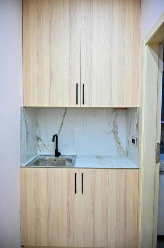 a kitchen with a sink and wooden cabinets at Andi Apartments in Durrës