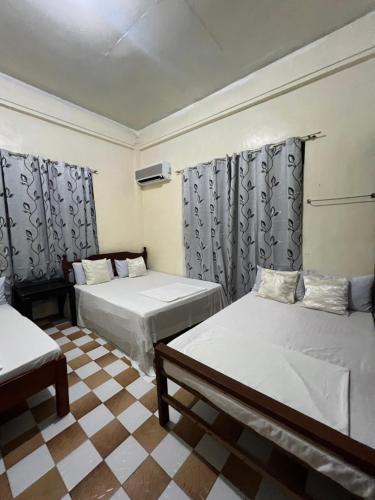 a room with two beds and a checkered floor at Besañes Homestay in Alaminos