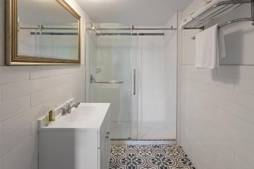 a white bathroom with a shower and a sink at Wildwood Inn Hotel Travelodge Beach & Boardwalk in Wildwood